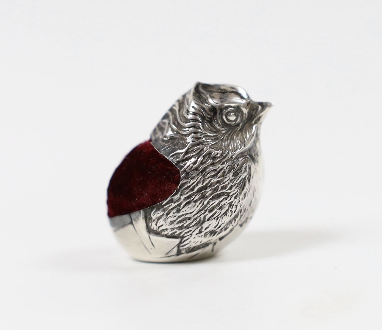An early 20th century novelty silver mounted pin cushion, modelled as a hatching chick, Chester, 19??, maker's mark and date letter rubbed, height 36mm.